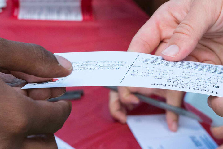 Close up of an invitation exchanging hands from one person to another.